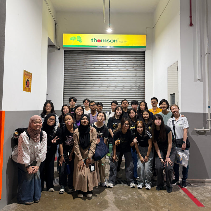 Group of people posing for a photo in an indoor setting with a Thompsons sign in the background.